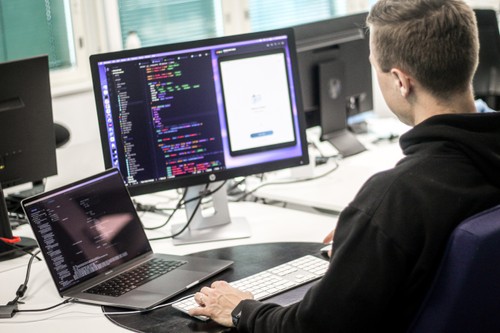 An office worker, who in addition to a laptop screen has a large external monitor