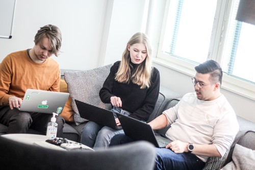 Three people working on their laptops on a corner couch